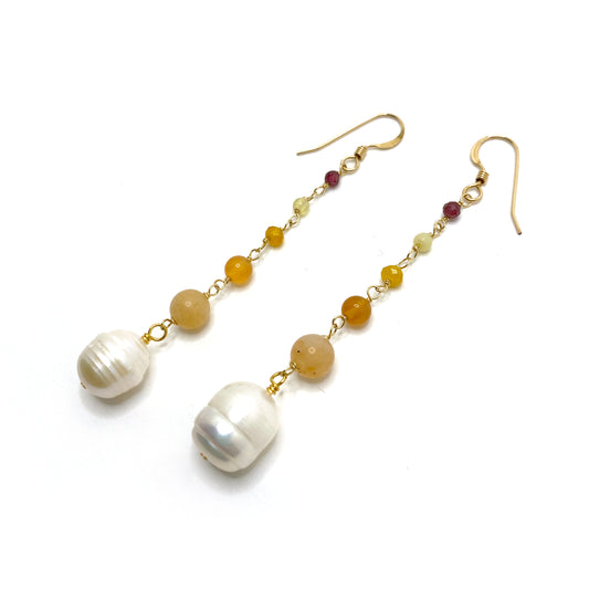 14k gold-filled hook earrings in the hues of a warm sunset. Beads connected by delicate wire wraps and increasing in size as they go down. Starting at the top with a tiny faceted garnet, a round yellow opal, a faceted dyed yellow quartz, a round orange agate, a round pale orange carnelian, and an oblong freshwater pearl.