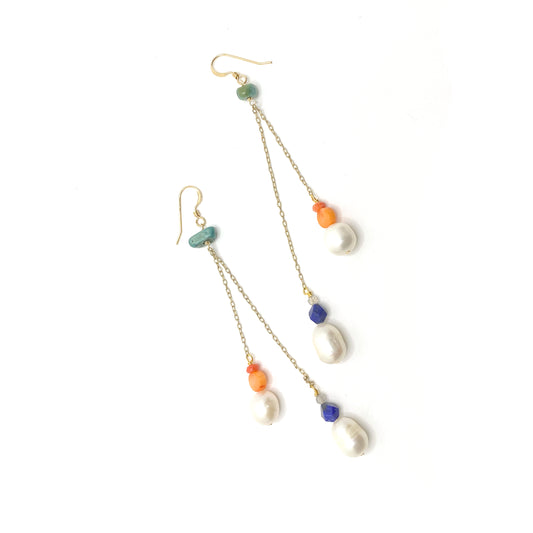 An ear hook with a wire-wrapped nugget of turquoise. From the turquoise hang two long pieces of gold-filled chain at different lengths. One has a small faceted labradorite, a lapis lazuli, and a freshwater pearl at the end. The other has a faceted piece of imitation coral over a round disc of vintage coral and a freshwater pearl.